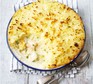 Creamy fish pie in a serving dish with a scoop out