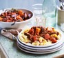 Sausage and carrot stew on pasta on plates
